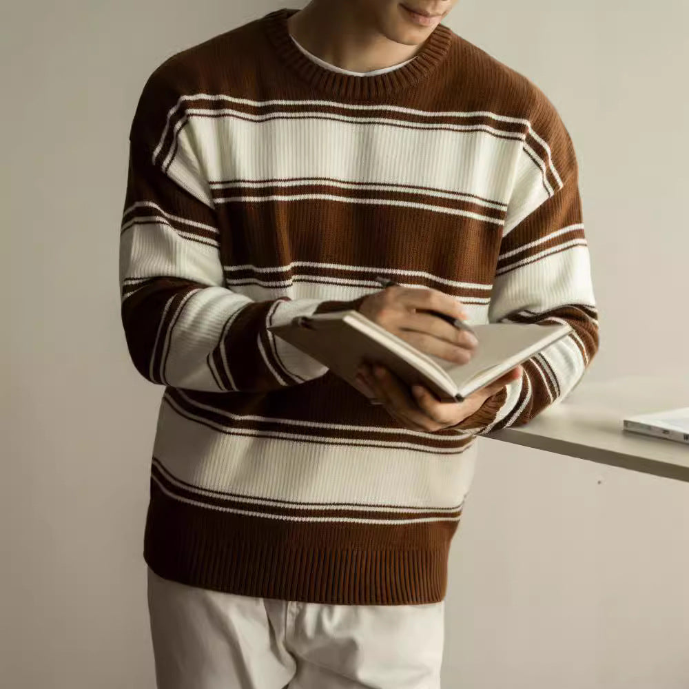 Man wearing a black and cream horizontal striped ribbed knit crewneck sweater with long sleeves.