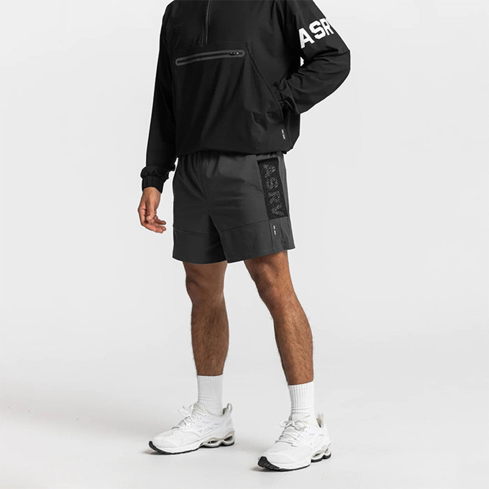 Man wearing black training shorts with mesh side pocket panel and white sneakers. 