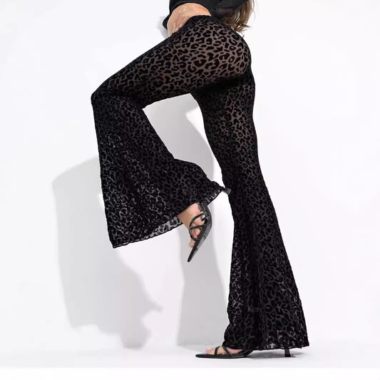 Woman wearing high-waisted black sheer mesh flare pants with leopard pattern and bell-bottom legs.