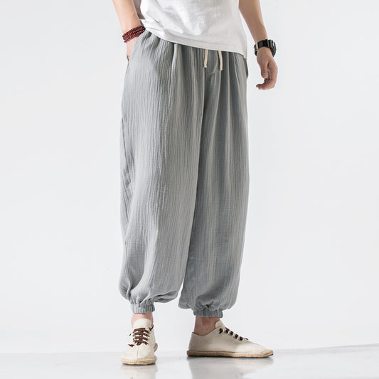 Man wearing beige loose-fit harem pants with drawstring waist and elastic ankle cuffs, styled with casual 
shoes for relaxed boho wear.