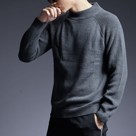 Man wearing a dark grey ribbed knit crewneck sweater with raglan sleeves. 
