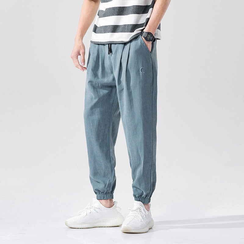 Man wearing relaxed fit casual jogger pants with drawstring waist and cuffed ankles paired with white 
sneakers.