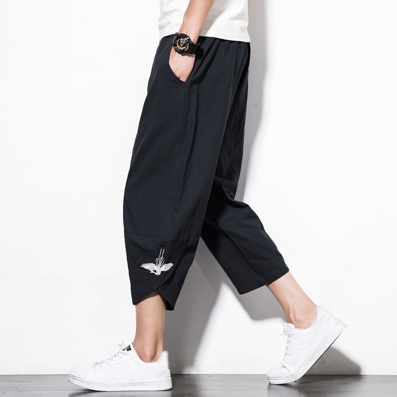Man wearing olive green cropped wide-leg drawstring pants with white sneakers. 