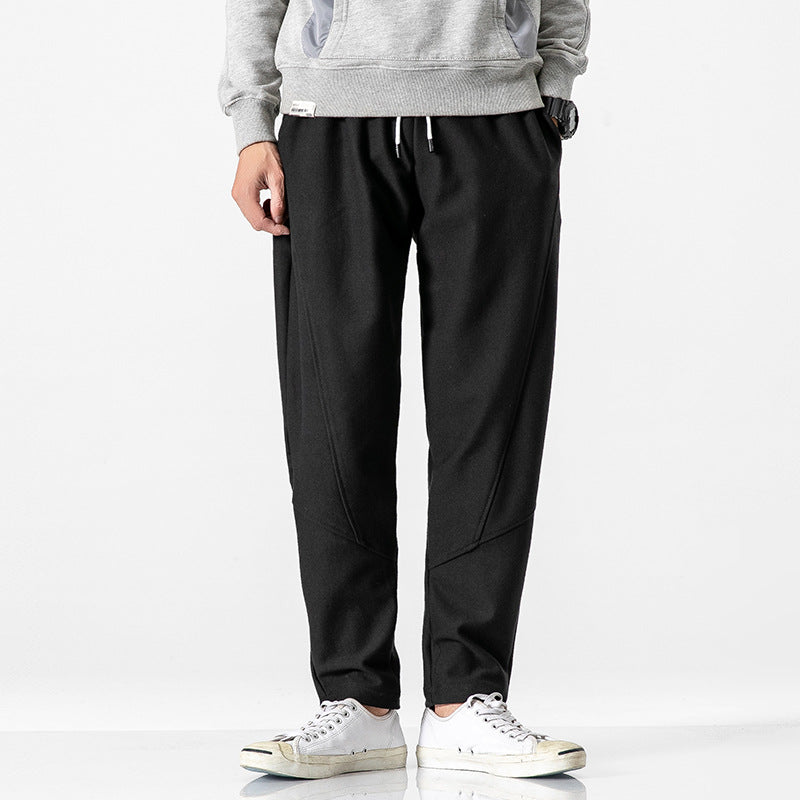 Man wearing black jogger pants, grey sweatshirt, and white sneakers, Threadspired fashion