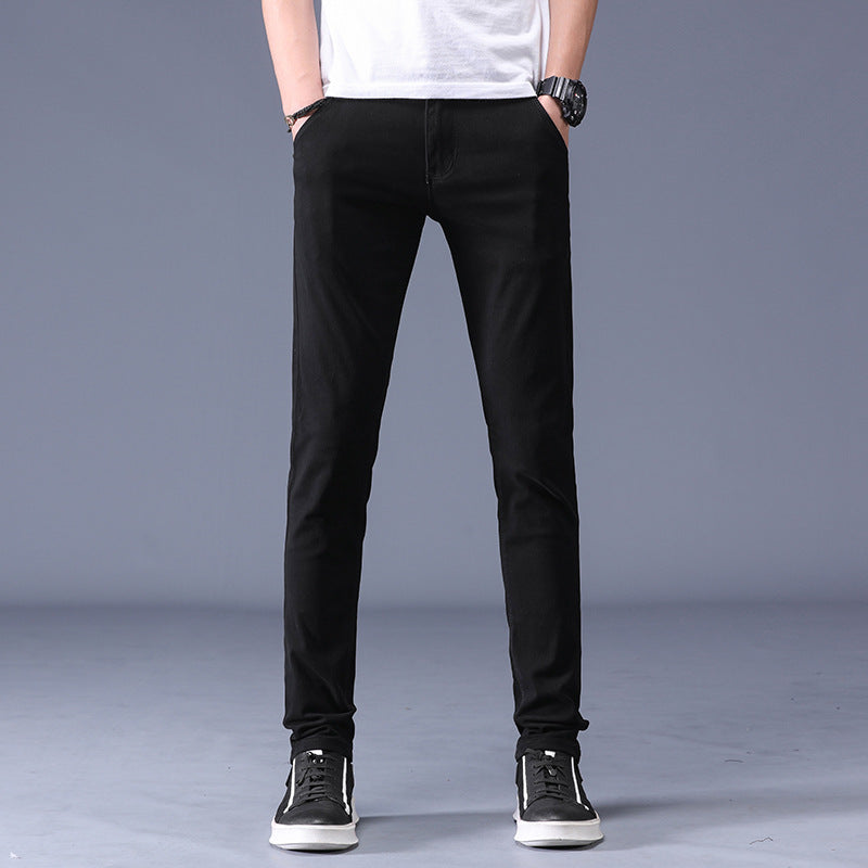 Men’s black slim fit casual pants worn with sneakers and a white T-shirt against a neutral background. 