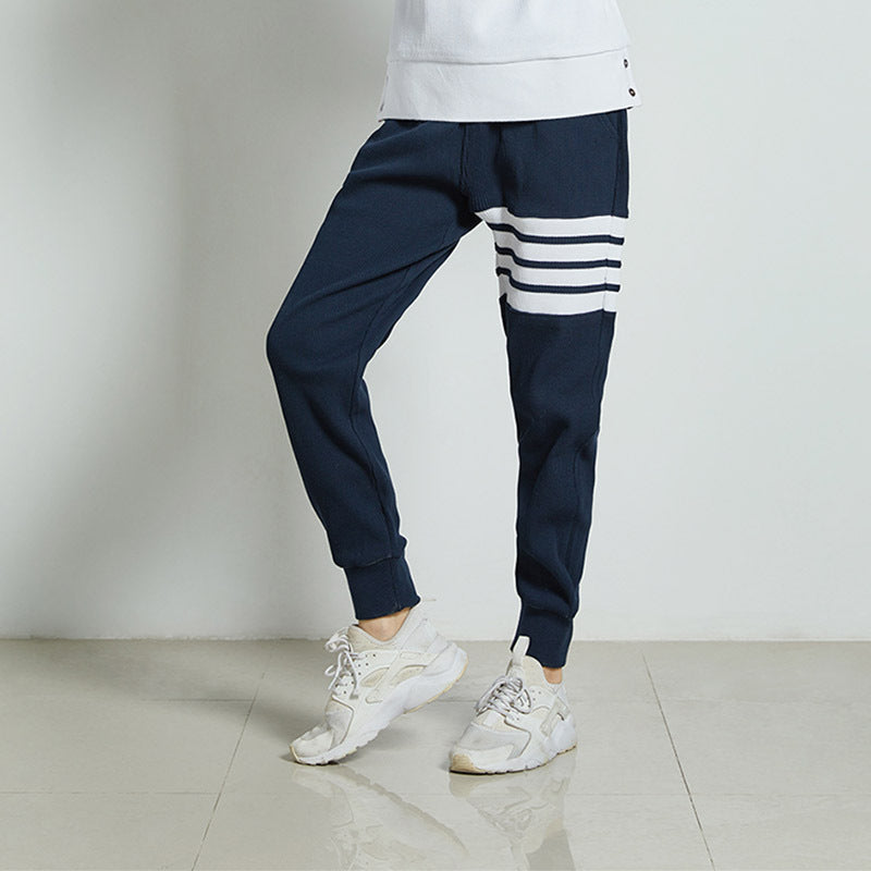 Black men’s jogger sweatpants with bold white stripe panel detail, drawstring waist, and ribbed ankle cuffs.