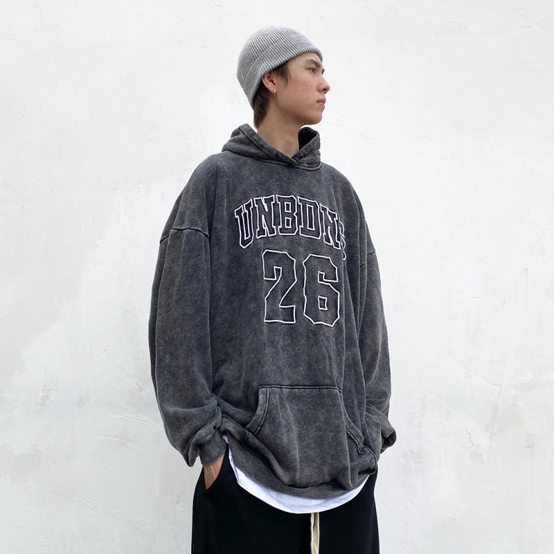 Vintage wash grey hoodie with “UNBDNS 26” varsity-style lettering on the front with a hood and pouch 
pocket against a white background.