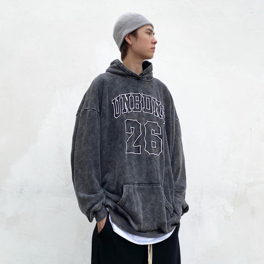 Vintage wash grey hoodie with “UNBDNS 26” varsity-style lettering on the front with a hood and pouch 
pocket against a white background.