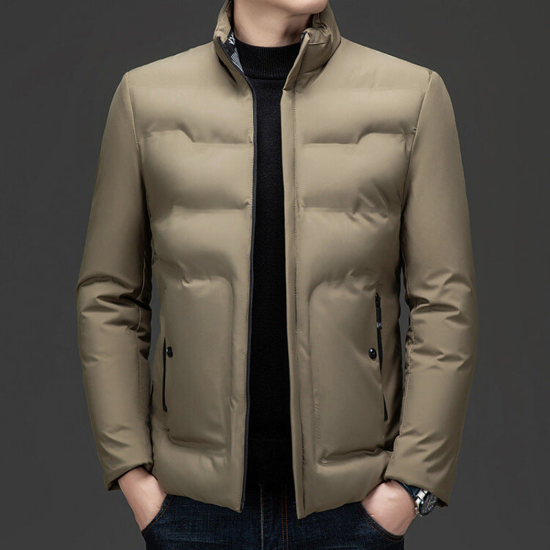Men wearing a beige lightweight puffer jacket with stand collar, slim fit design, and zippered pockets on a 
dark background. 