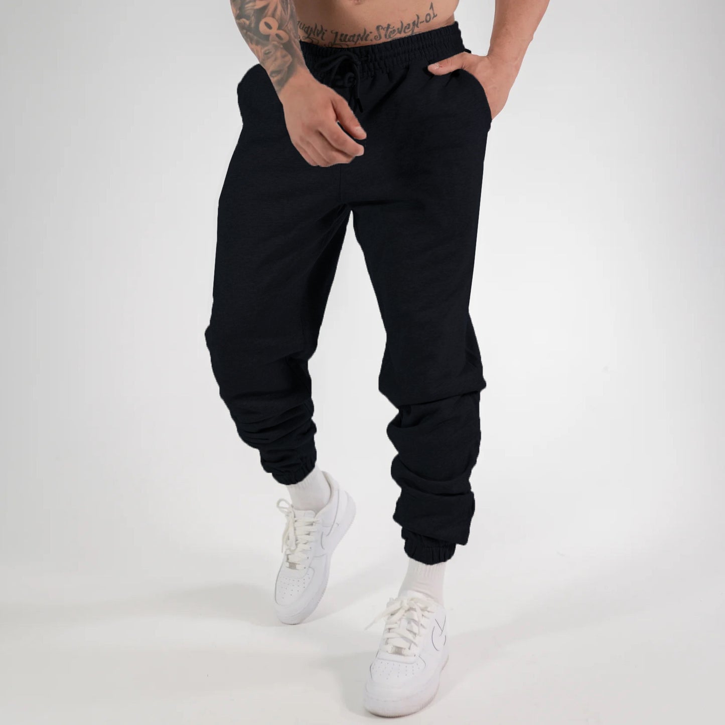 Man wearing black heavyweight jogger sweatpants with elastic waistband and cuffed ankles paired with 
white sneakers. 