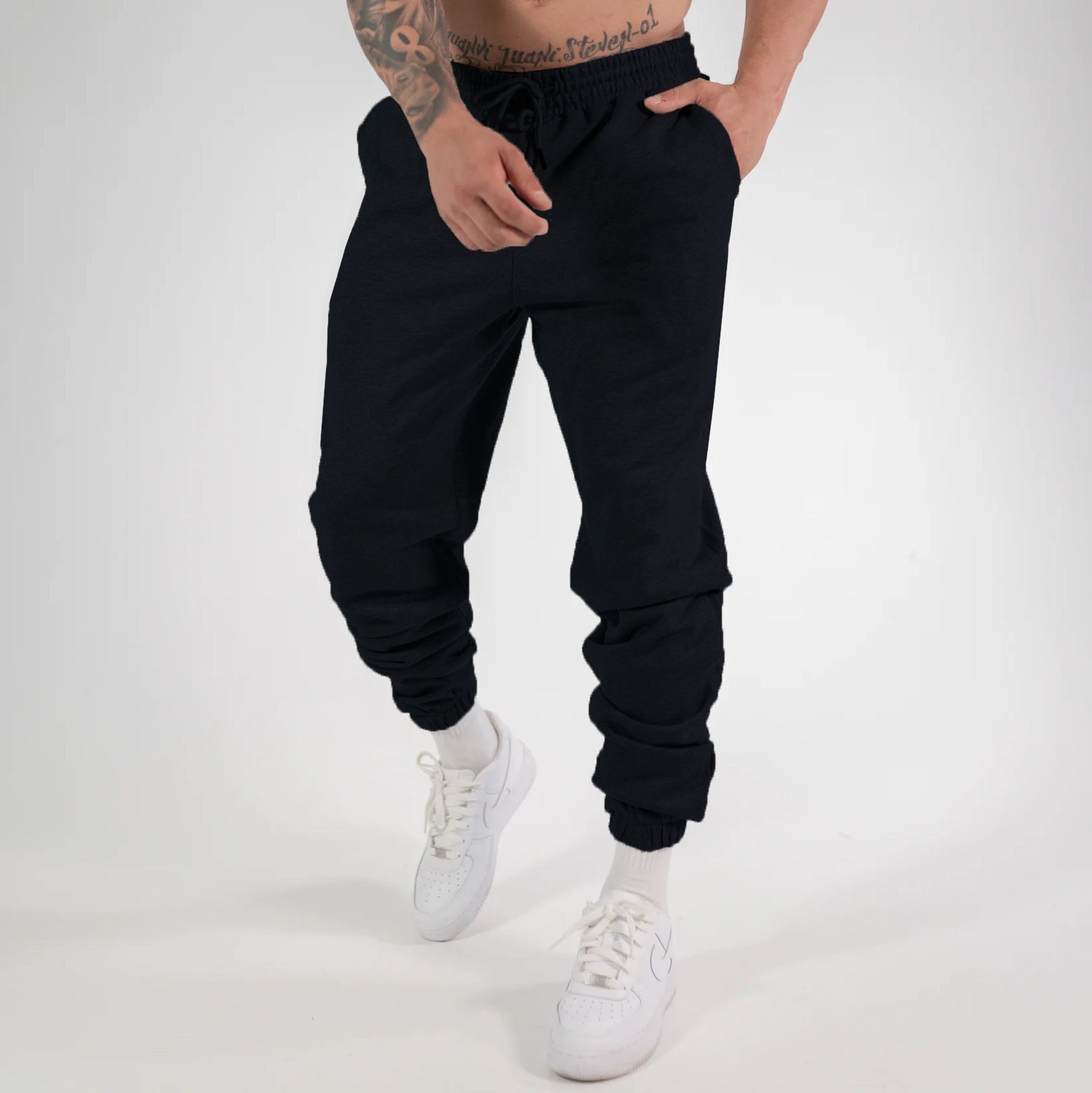Man wearing black heavyweight jogger sweatpants with elastic waistband and cuffed ankles paired with 
white sneakers. 