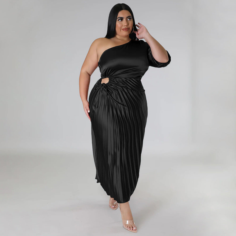 Plus size model wearing a black one-shoulder pleated long midi dress with side cutout and asymmetrical 
sleeve, styled with clear high heels. 