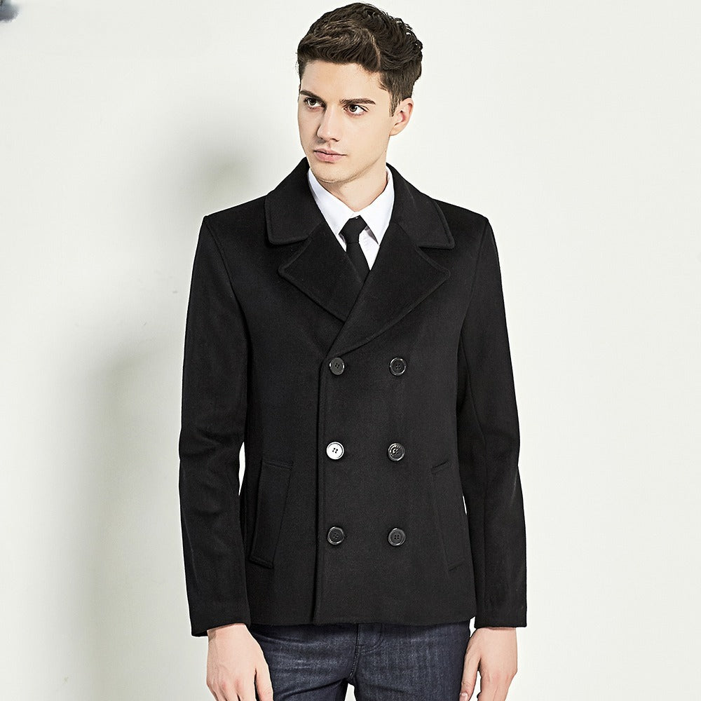 Man wearing a black double-breasted semi-length coat with notch lapel and jeans. 