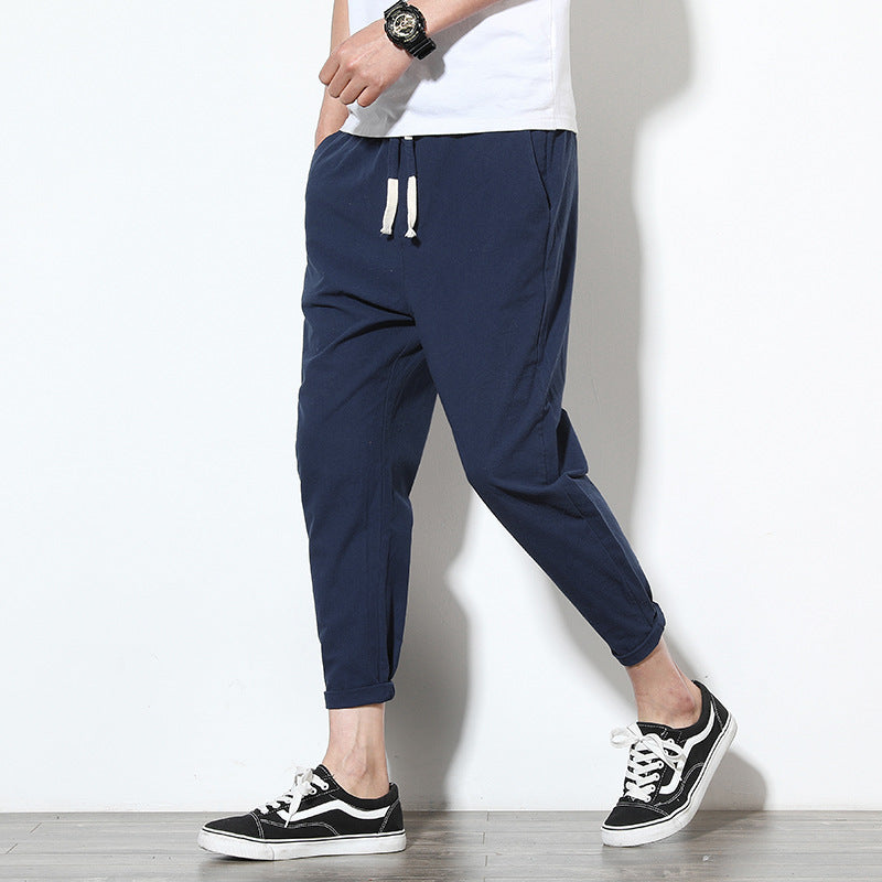 Man wearing navy slim-fit ankle-length pants with drawstring waist and black sneakers, styled as casual 
streetwear