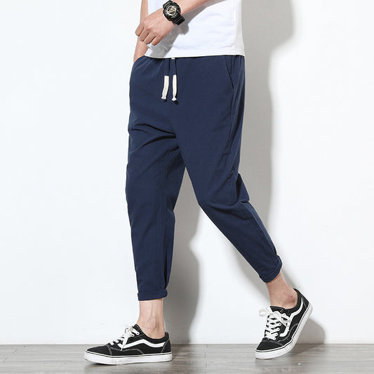 Man wearing navy slim-fit ankle-length pants with drawstring waist and black sneakers, styled as casual 
streetwear