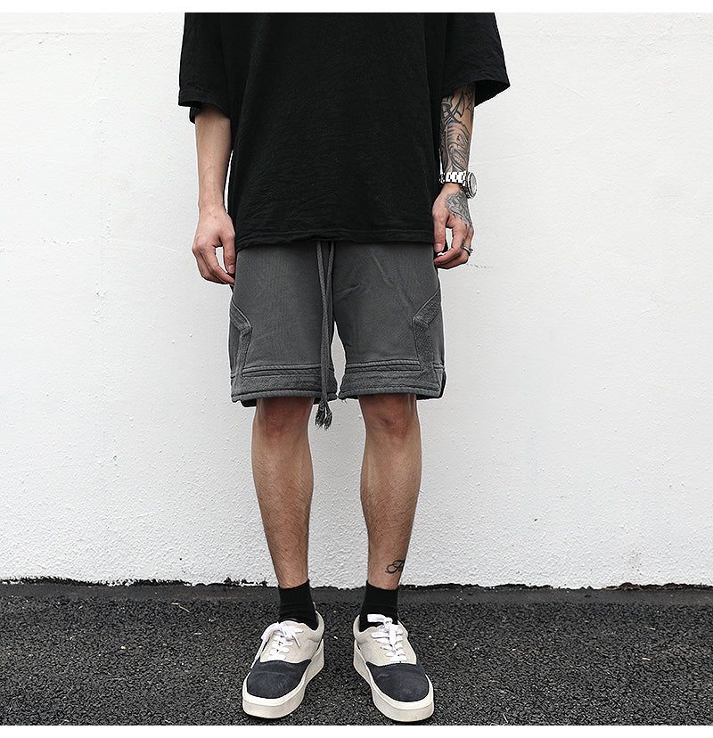 Man wearing washed black cargo-style streetwear shorts with oversized black t-shirt and skate sneakers. 