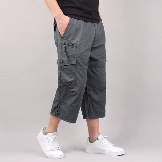 Man wearing olive green multi-pocket cargo capri pants. 