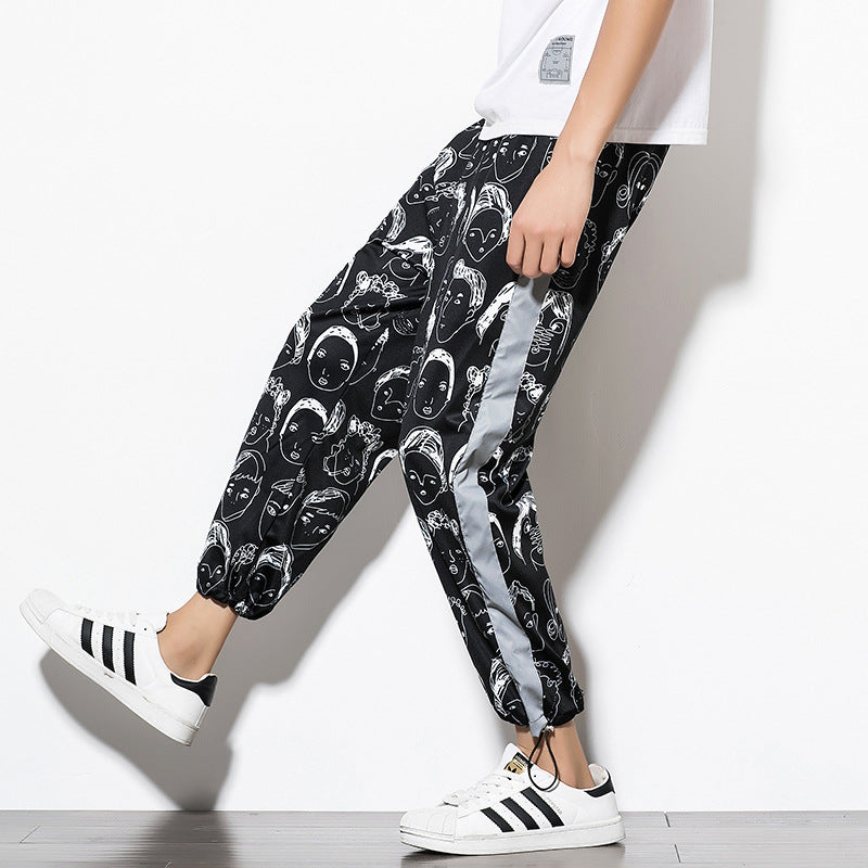 Man wearing black jogger pants with white graphic face print and luminous side stripe.