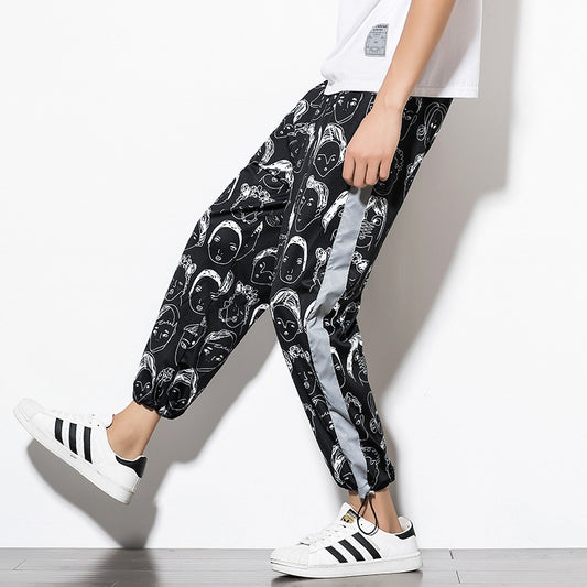 Man wearing black jogger pants with white graphic face print and luminous side stripe.