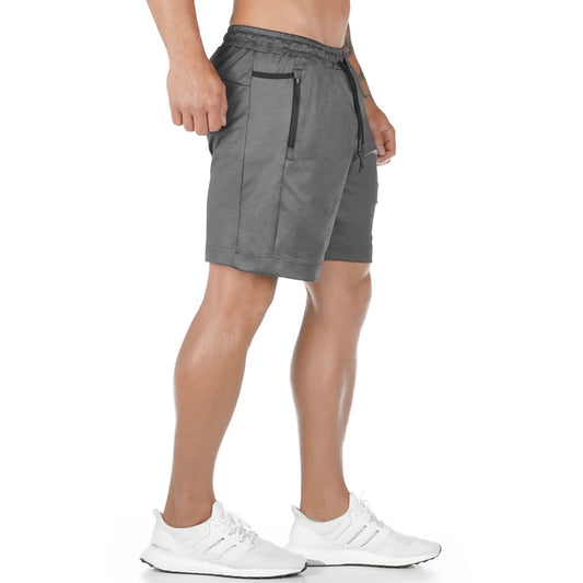 Man wearing black lightweight athletic training shorts with elastic waistband and white running shoes.