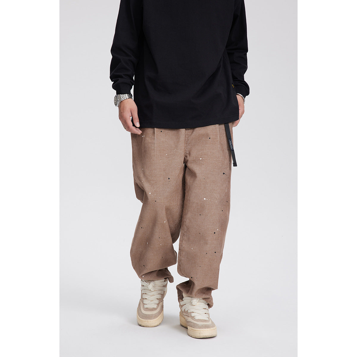 Men’s dark wash cropped pants with paint splatter detail and adjustable waist strap.