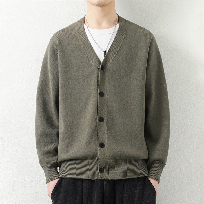 Man wearing an olive green V-neck button-down knit cardigan sweater layered over a white shirt.