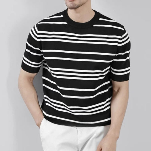 Man wearing a cream and black striped short-sleeve knit T-shirt styled with black trousers.