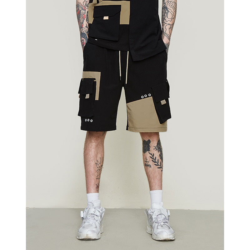 Man wearing black and khaki techwear cargo shorts with multiple utility pockets and white sneakers.