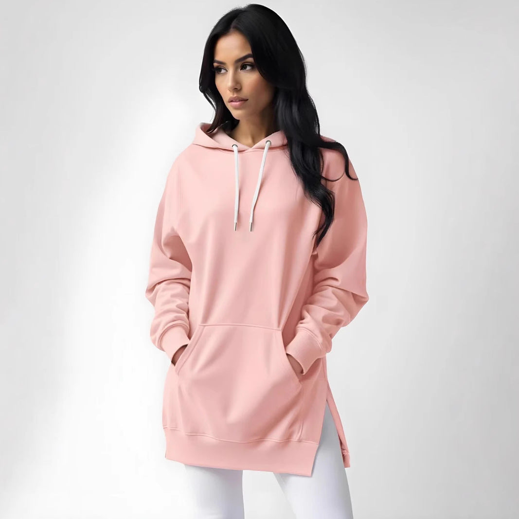 Woman wearing an oversized grey pullover hoodie with drawstring hood and front pouch pocket, styled with 
black leggings.
