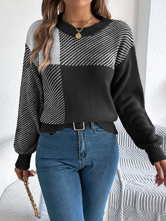 Woman wearing a black and grey geometric patchwork knit sweater with mixed patterns, styled with blue 
jeans, gold jewelry and a belt. 