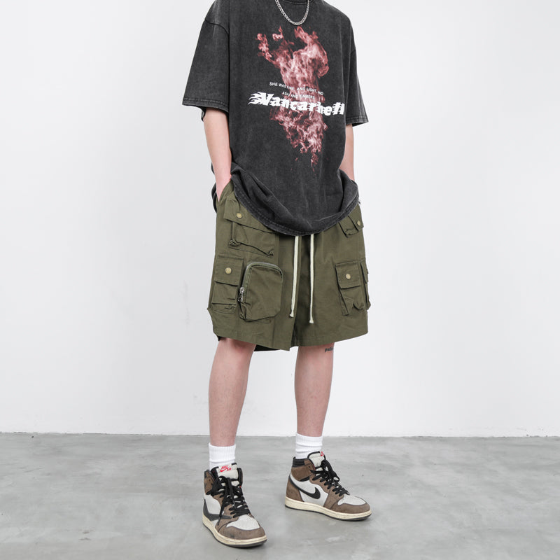 Man wearing oversized black multi-pocket cargo streetwear shorts with graphic t-shirt and high-top 
sneakers. 