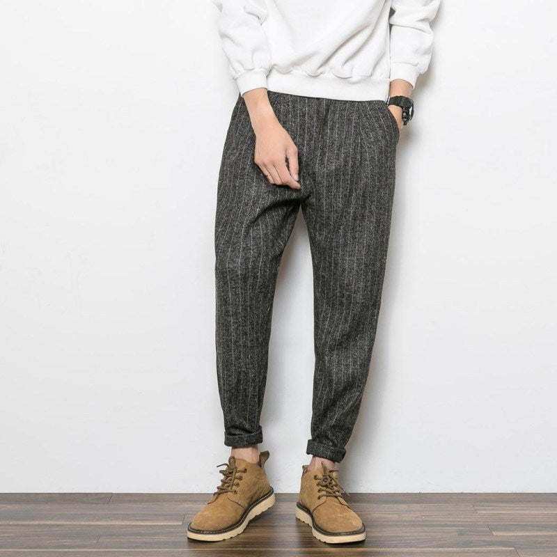 Man wearing charcoal grey slim tapered casual pants with textured fabric, styled with a sweatshirt and 
boots. 
