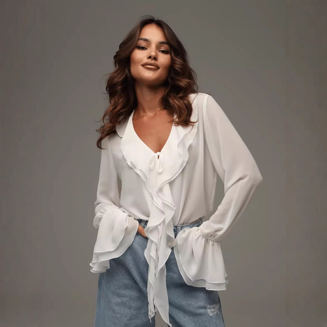 Woman wearing a white ruffle V-neck long sleeve chiffon blouse with flared cuffs, styled with denim pants.