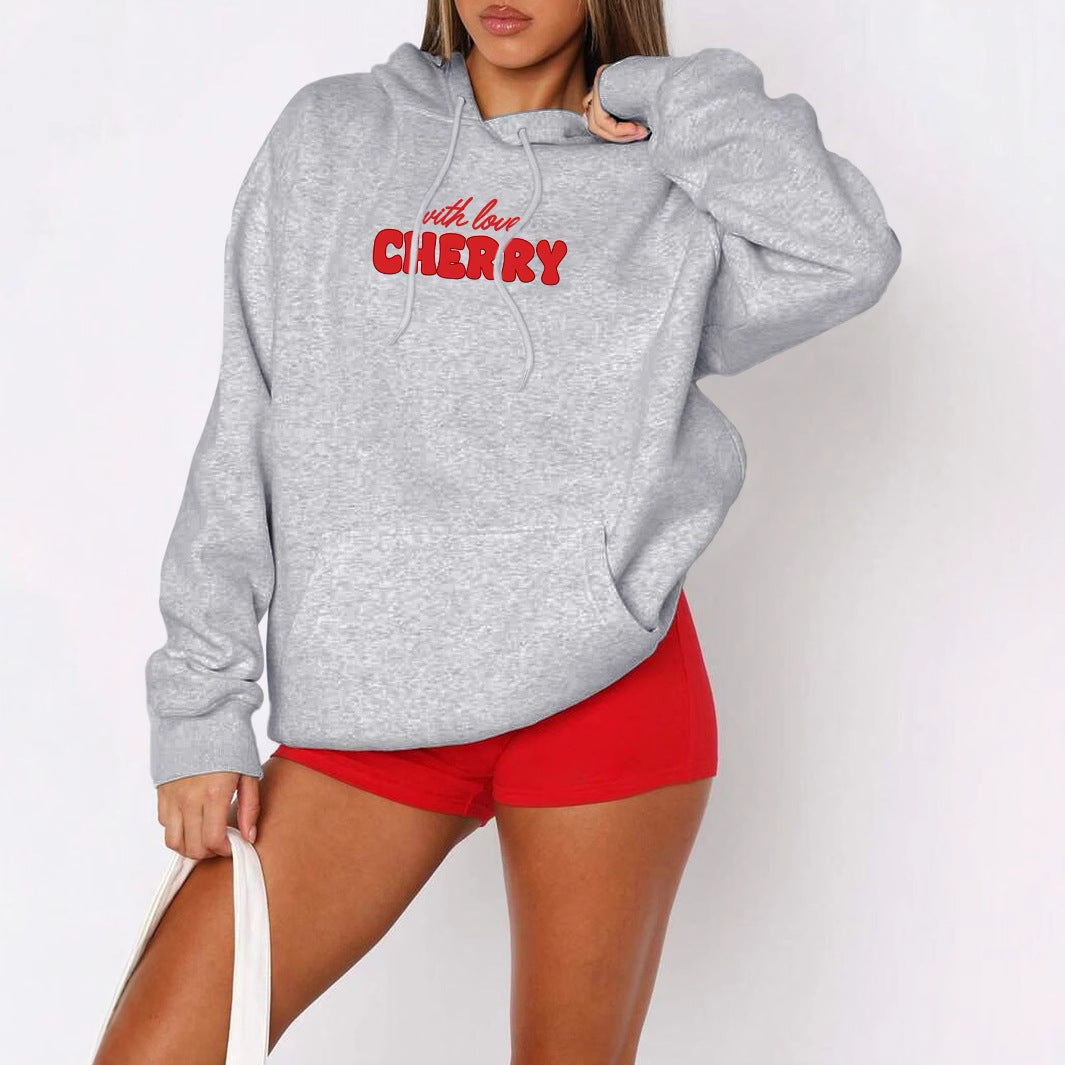 Woman wearing a grey oversized pullover hoodie with red “with love Cherry” text graphic on the front, back 
detail of cherry artwork and text.