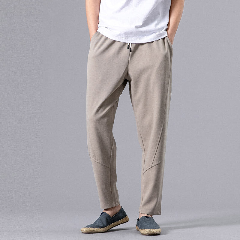 Man wearing white relaxed-fit jogger pants with drawstring waist and casual shoes. 