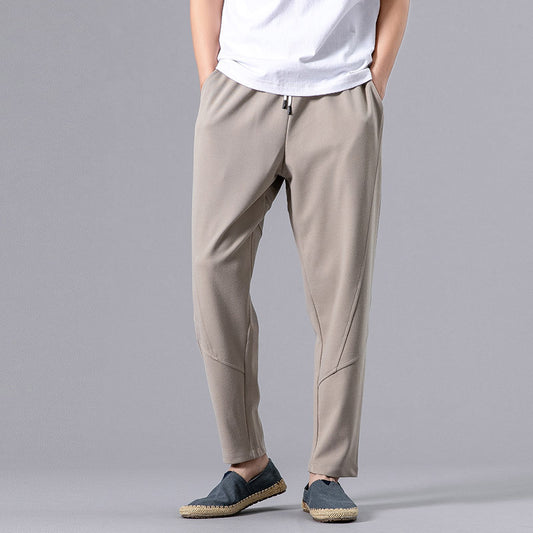 Man wearing white relaxed-fit jogger pants with drawstring waist and casual shoes. 