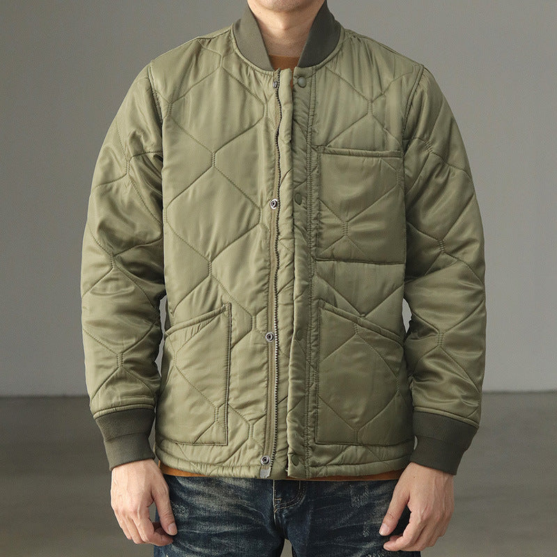 Man wearing an olive green quilted jacket coat with ribbed cuffs and collar, lightweight insulated.