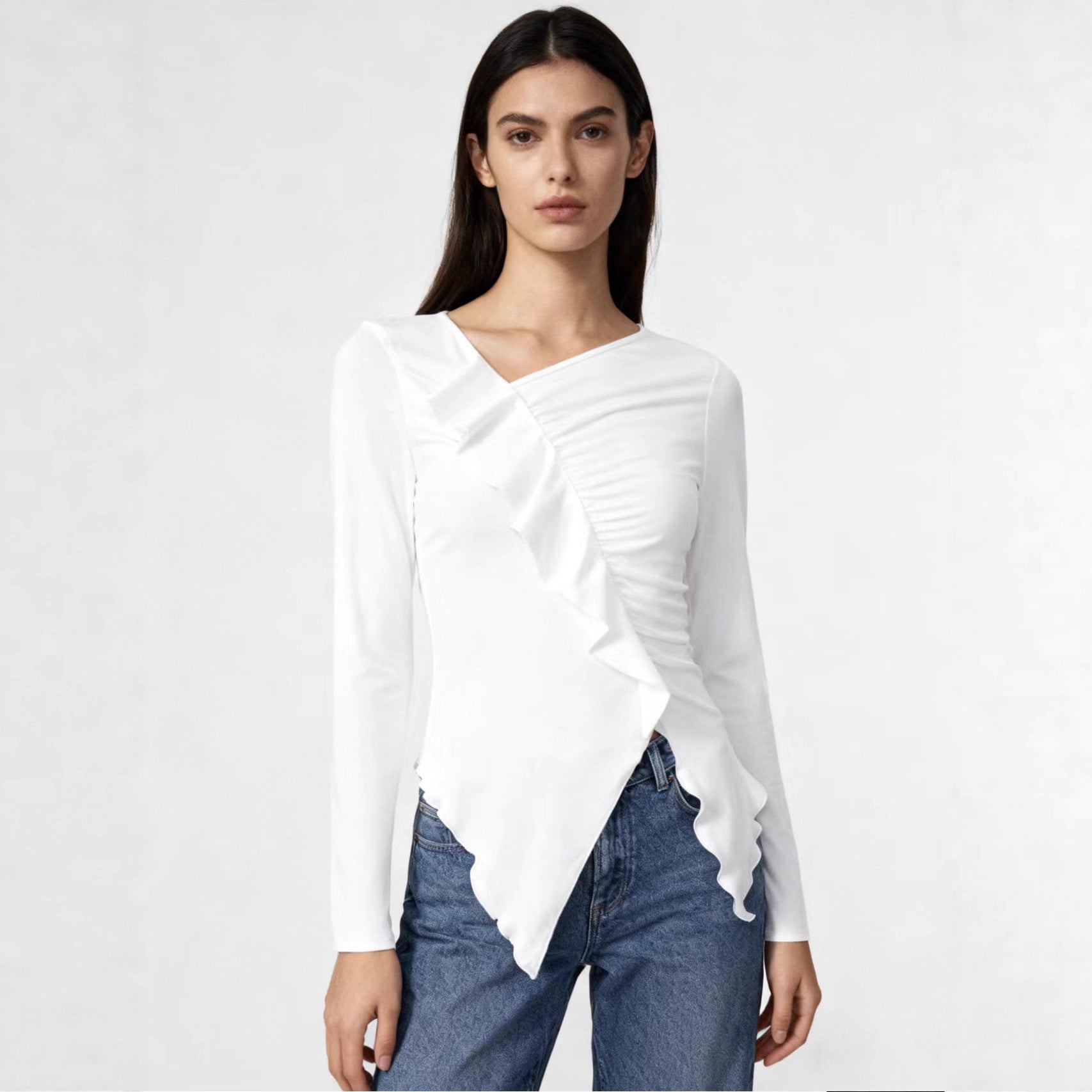 Woman wearing a burgundy asymmetrical long sleeve wrap top with ruffle detailing.