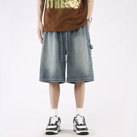 Man wearing loose fit washed denim knee-length shorts with white socks and black sneakers.