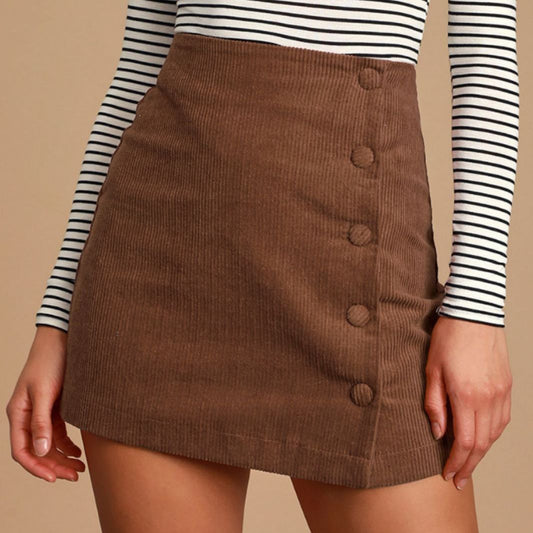 Woman wearing a high-waisted brown corduroy mini skirt with button-front detail and A-line silhouette, 
styled with a strippy top. 