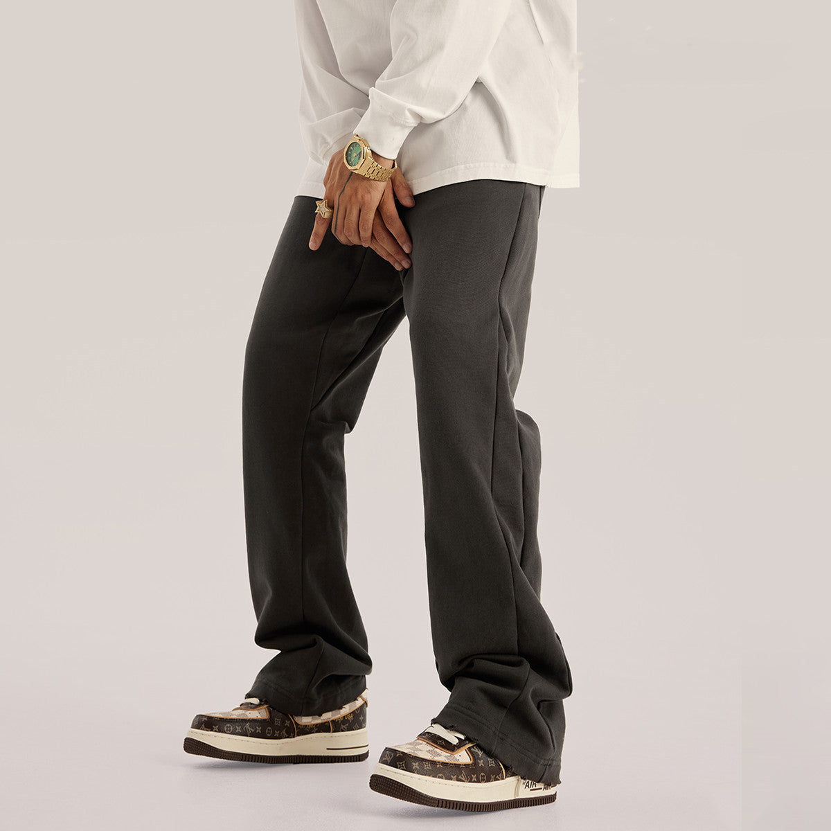 Men’s light grey wide-leg sweatpants with elastic waistband, side pockets, and raw hem detail displayed on 
a white background.