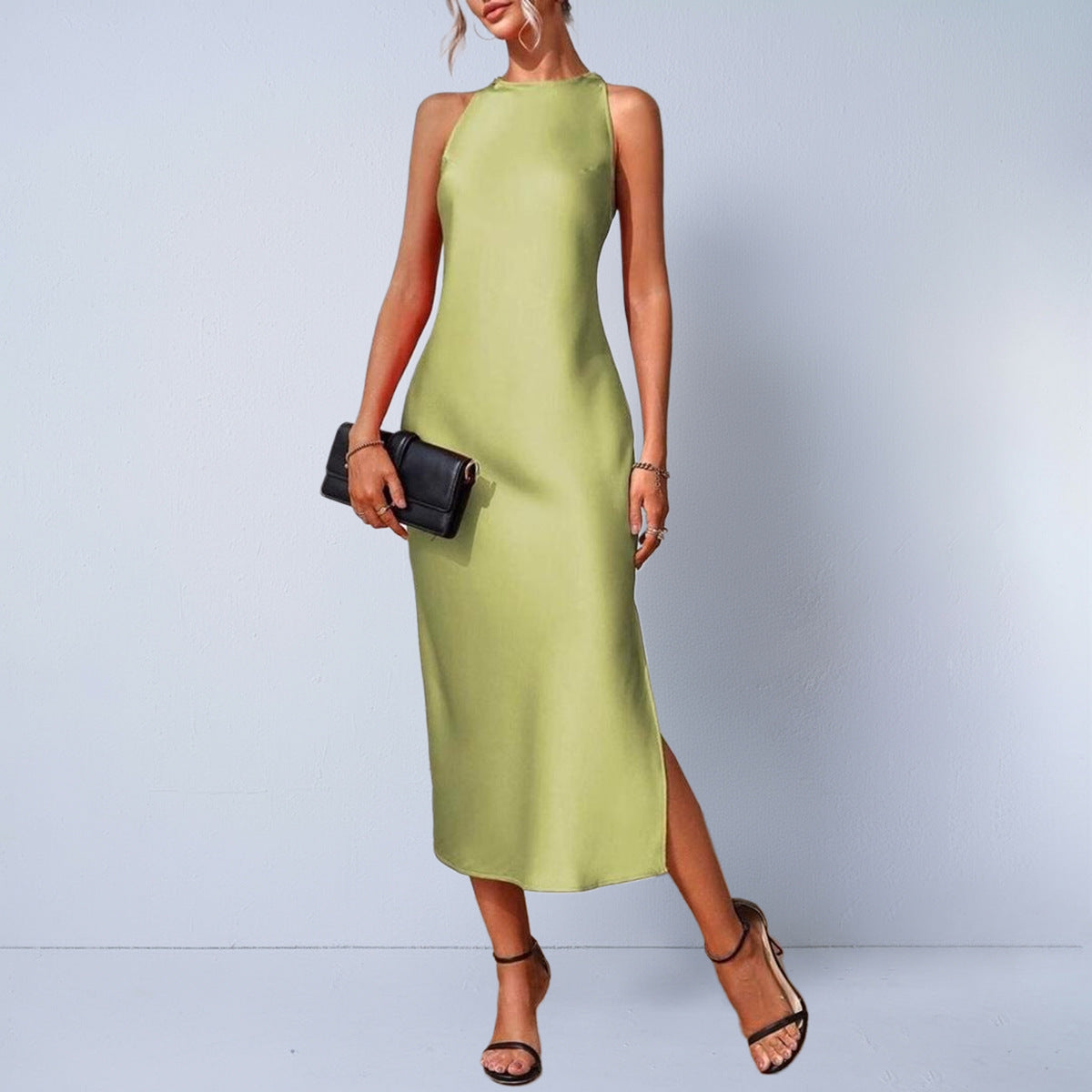 Woman wearing a creme satin sleeveless long midi dress with high neckline, styled with black purse and 
heels. 