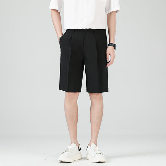 Man wearing beige tailored knee-length shorts styled with a black shirt and white sneakers.
