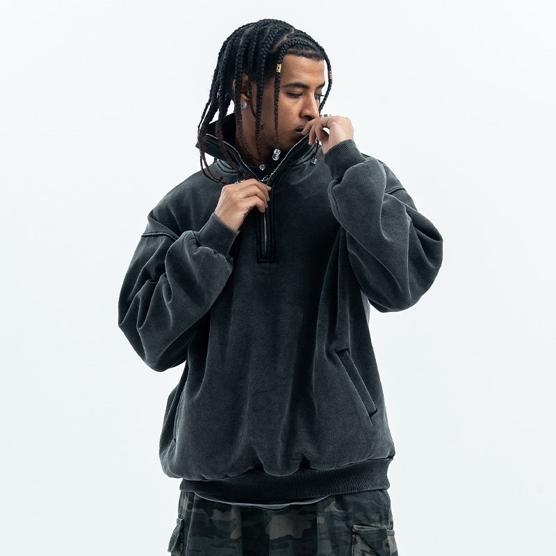 Man wearing an oversized washed black half-zip sweatshirt. 