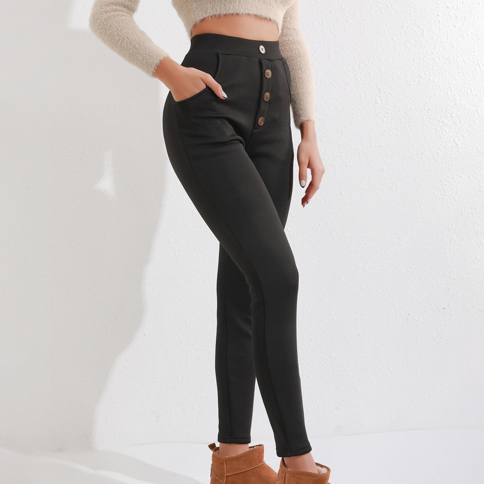 Woman wearing high-waisted black button-front leggings with pockets and ankle-length slim fit.