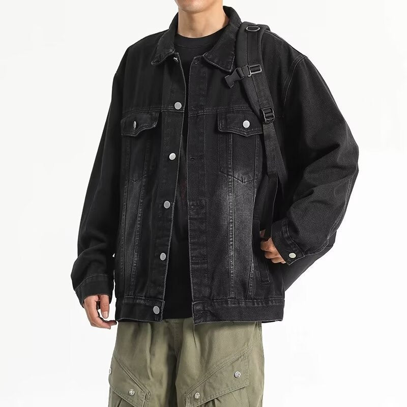 Man wearing a black denim jacket with button front, chest flap pockets. 