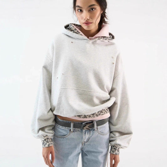 Women’s pullover hoodie in grey with leopard print cuffs and hem, small ripped cut-out details. 
