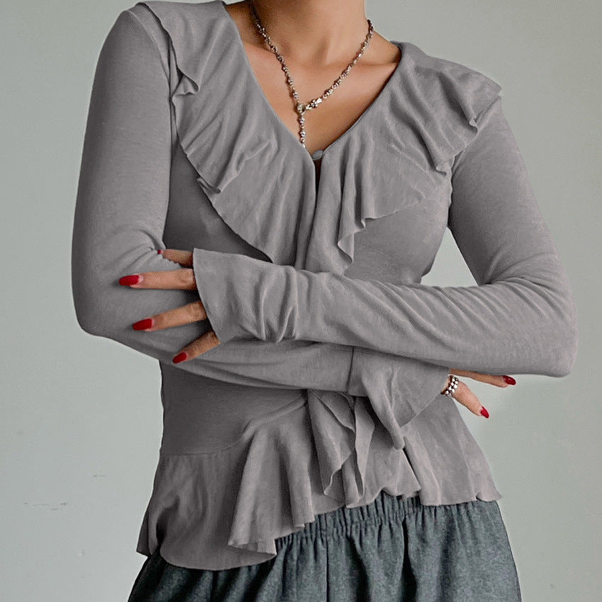 Woman wearing an ivory long sleeve V-neck blouse with ruffle detailing. 
